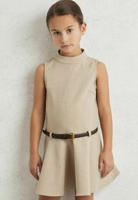 Vestido sin mangas de color beige con un cuello alto, una falda acampanada y un cinturón marrón con una hebilla en tono dorado. Tejido suave con una textura sutil.