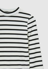 Top bianco a maniche lunghe con righe verticali nere, caratterizzato da una trama a coste e un colletto alto.