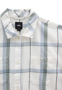 Chemise blanche à boutonnière avec un grand motif à carreaux bleu clair et vert, poche poitrine avec bouton, et étiquette Vans sur le col.