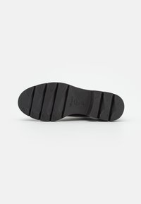 Semelle de chaussure noire avec des rainures profondes pour une meilleure traction, taille 37, présentée à plat sur un fond blanc.