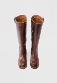 Καφέ δερμάτινες μπότες μέχρι το γόνατο με λείο φινίρισμα, στρογγυλεμένη μύτη και ελαφρώς υφασμένη σόλα. Διαθέτουν φερμουάρ στην εξωτερική πλευρά.