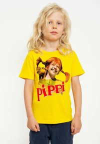 Yellow cotton t-shirt featuring a graphic print of a girl with red pigtails and a monkey, with the word "PIPPI" in bold red letters.