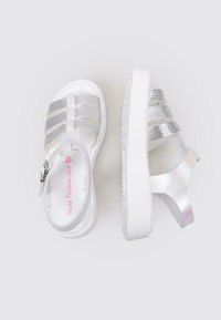 Sandalias blancas con correas metálicas plateadas, con un diseño texturizado y una suela de plataforma. Hebilla ajustable para un mejor ajuste, acabado suave.