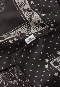 Sort silkescarf med indviklede elfenbensmønstre med prikker og blomsterdesigns, mærket med et lille skilt, der står "BECK SÜNDERGAARD."