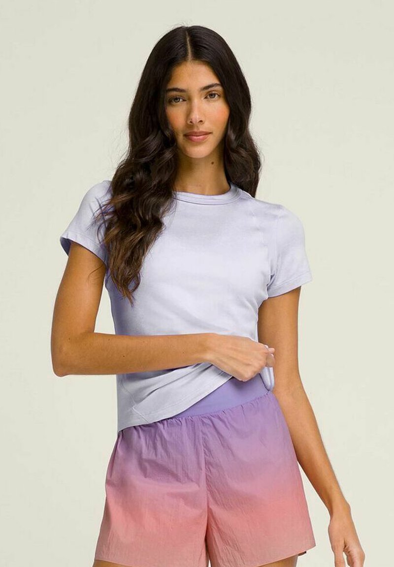 Camiseta de manga corta color morado claro hecha de tejido suave, combinada con pantalones cortos en degradado de rosa a morado. Diseño simple con cuello redondo y ajuste relajado.