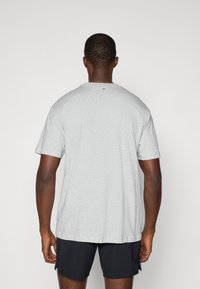 Sivá krátkareký tričko s uvoľneným strihom a okrúhlym výstrihom, s malým zeleným akcentom pri zadnom golieri.