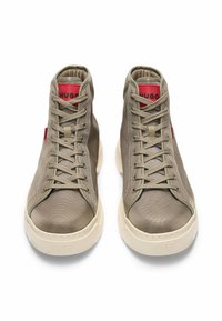 Høje sneakers i olivengrønt stof med beige gummisål. Har snørebånd, polstret krave og rød logoaccent.