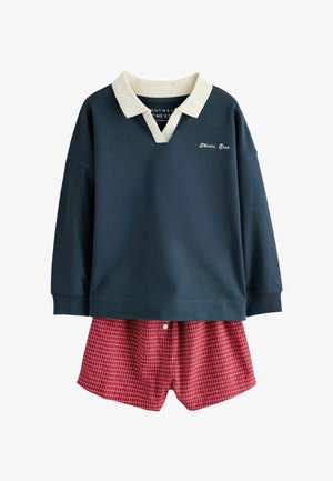 Granatowa koszulka polo z długim rękawem, białym kołnierzem i napisem „Athletic Club”, połączona z czerwonymi szortami w kratę z przednim guzikiem.