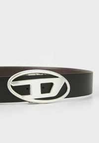 Black leather belt with a polished silver oval buckle featuring a stylized "D" design. Textured interior with adjustable holes.