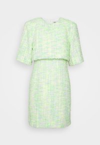 Robe deux pièces texturée vert clair et blanche avec manches courtes et jupe ajustée sur fond uni.