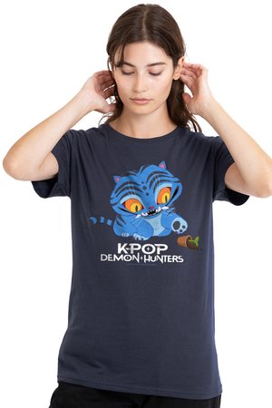 Junge Frau, die ihre Haare richtet, trägt ein marineblaues T-Shirt mit einem Cartoon eines blauen Tigers, dem Schriftzug "K-POP DEMON HUNTERS" und einer Grafik eines umgestürzten Blumentopfs.