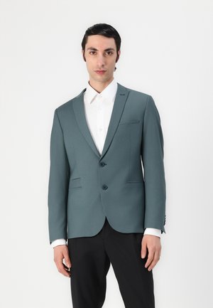 Slim-fit, teal blazer with two buttons, notch lapels, and black trousers. Features shoulder padding and two front pockets. White shirt underneath.