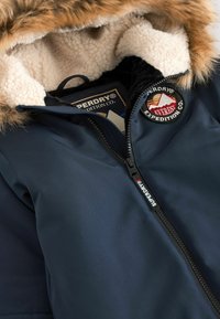 Dunkelblaue Winterjacke mit einem Kunstpelz-Kapuzendetail, Fleece-Futter und einem markanten Logo-Patch. Verfügt über einen langlebigen Reißverschluss und ein elegantes Design.