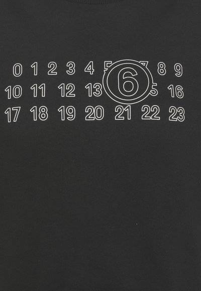 T-shirt nera con numeri bianchi stampati disposti in un motivo a griglia, con un cerchio prominente attorno al numero 6. Texture liscia.