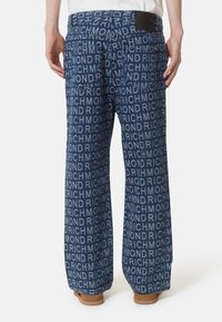Pantaloni in denim a gamba larga caratterizzati da un motivo ripetuto con il logo "RICHMOND" in toni di blu scuro e blu chiaro; includono due tasche posteriori e dettagli in pelle sulla cintura.