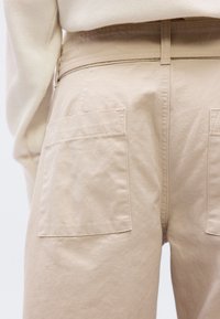 Μπεζ παντελόνι εργασίας με δύο μεγάλες πίσω τσέπες, εφαρμοστή μέση και ομαλό, ελαφρώς  υφασμένο ύφασμα.