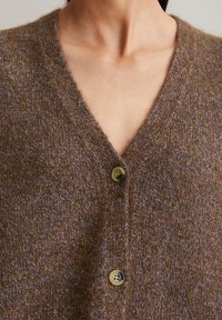 Brown knitted cardigan with a V-neck, featuring two large buttons and a textured fabric that has subtle blue flecks.