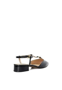 Chaussure à talon ouvert en cuir noir avec un bout pointu, un petit talon carré et une sangle à boucle en accent. Texture lisse et design minimaliste.