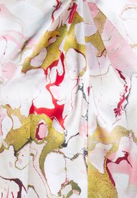 Tissu présentant un design marbré avec des accents rose, rouge et doré sur un fond blanc ; texture lisse avec des drapés fluides.