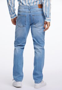 Jeans de mezclilla azul claro con un corte relajado, que cuentan con una cintura de altura media, bolsillos traseros y una etiqueta de cuero marrón en la cinturilla.
