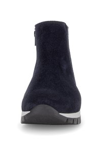 Bottes chelsea en suede bleu marine avec une semelle en caoutchouc texturé noir et fermeture éclair sur le côté, présentées de face sur fond blanc.