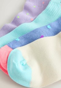 Vier paar kleurrijke katoenen sokken met pasteltinten en kleine meerkleurige stippen, netjes overlappend uitgestald op een lichte ondergrond.