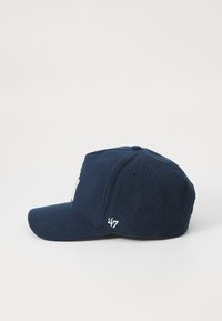 Navy corduroy cap with a curved brim, featuring white embroidered logo and text on the side. The texture is ribbed and soft.