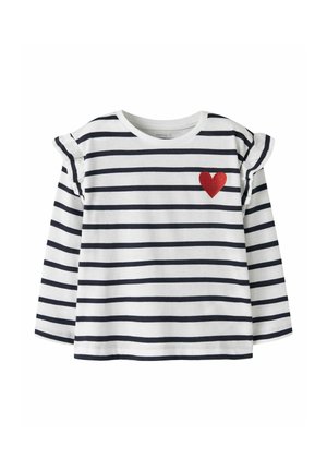 Chemise blanche à manches longues avec des rayures horizontales noires, des épaules à volants et un petit cœur rouge sur la poitrine gauche.