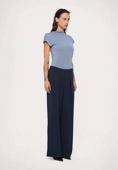 Top azul de manga curta com decote elevado, combinado com calças largas em marinho escuro, apresentando uma cintura reta e uma textura suave.