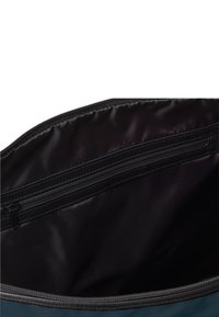 Dunkles, leeres Innere einer Tasche mit einem Reißverschlusstaschen an der Oberseite. Die äußeren Kanten zeigen die Nähte und die Textur der Tasche.