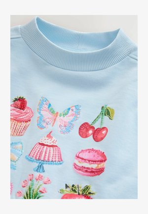 Felpa azzurro chiaro con ricami colorati di dolci, una farfalla e ciliegie, con scollatura a coste.
