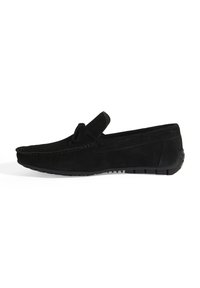Mocassin slip-on en daim noir avec une texture lisse, des coutures le long de la tige et une semelle en caoutchouc pour l'adhérence. Aucun matériel visible.