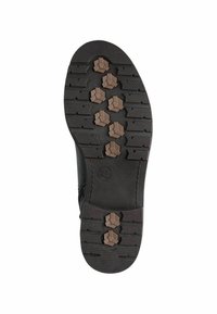 Black rubber boot sole with textured tread pattern, featuring hexagonal traction studs in brown and horizontal grooves for grip.