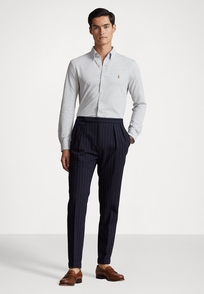 Gray long-sleeve button-up shirt with a collar, paired with navy pinstriped trousers and brown leather shoes. Casual yet refined outfit.