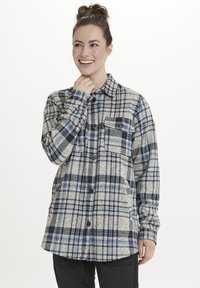 Ruiten flanellen overhemd in beige, navy en lichtblauw. Beschikt over een knoopsluiting aan de voorkant, twee borstzakken en een relaxte pasvorm.