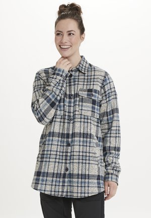 Chemise en flanelle à carreaux beige, marine et bleu clair. Présente une fermeture à boutons sur le devant, deux poches poitrine et une coupe décontractée.