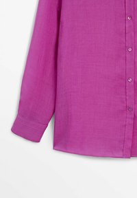 Chemise violette à manches longues boutonnée avec poignet visible et partie avant sur fond blanc.