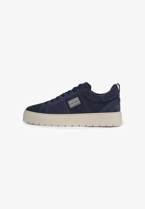 Marineblaue Wildleder-Sneaker mit beiger dicker Gummisohle, Schnürung vorne und rechteckigem Markenpatch an der Seite, seitlich dargestellt.