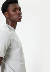 Lichtgrijs T-shirt met ronde hals en korte mouwen, gemaakt van zacht materiaal, met een subtiele textuur en een losse pasvorm.