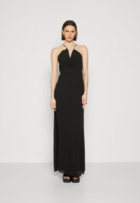 Rochie neagră cu gât halter, cu un bust drapat, design până la podea, material neted și fante laterale; accesorizată cu un colier cu perle.