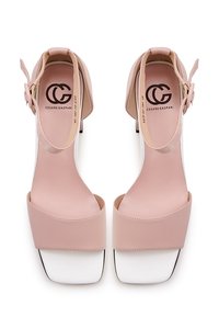 Sandales à talons hauts en cuir rose avec une large mentonnière et une bride de cheville, présentant un bout carré blanc et un logo sur la semelle intérieure.
