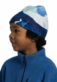 Colorful beanie made of soft fabric, featuring a blue and white abstract pattern. Worn by a child, with curls visible beneath the hat.