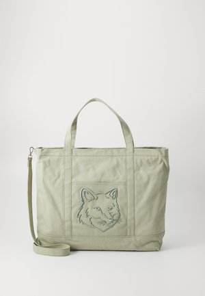 Borsa a tracolla verde in tela con un design ricamato di una faccia di volpe. Presenta due manici robusti e una tracolla regolabile. Texture liscia.