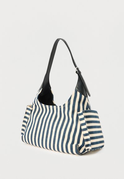 Ριγέ μπλε και λευκή υφασμάτινη τσάντα ώμου με μαύρη δερμάτινη λαβή και πλαϊνές τσέπες, πλάγια όψη σε μονόχρωμο φόντο.