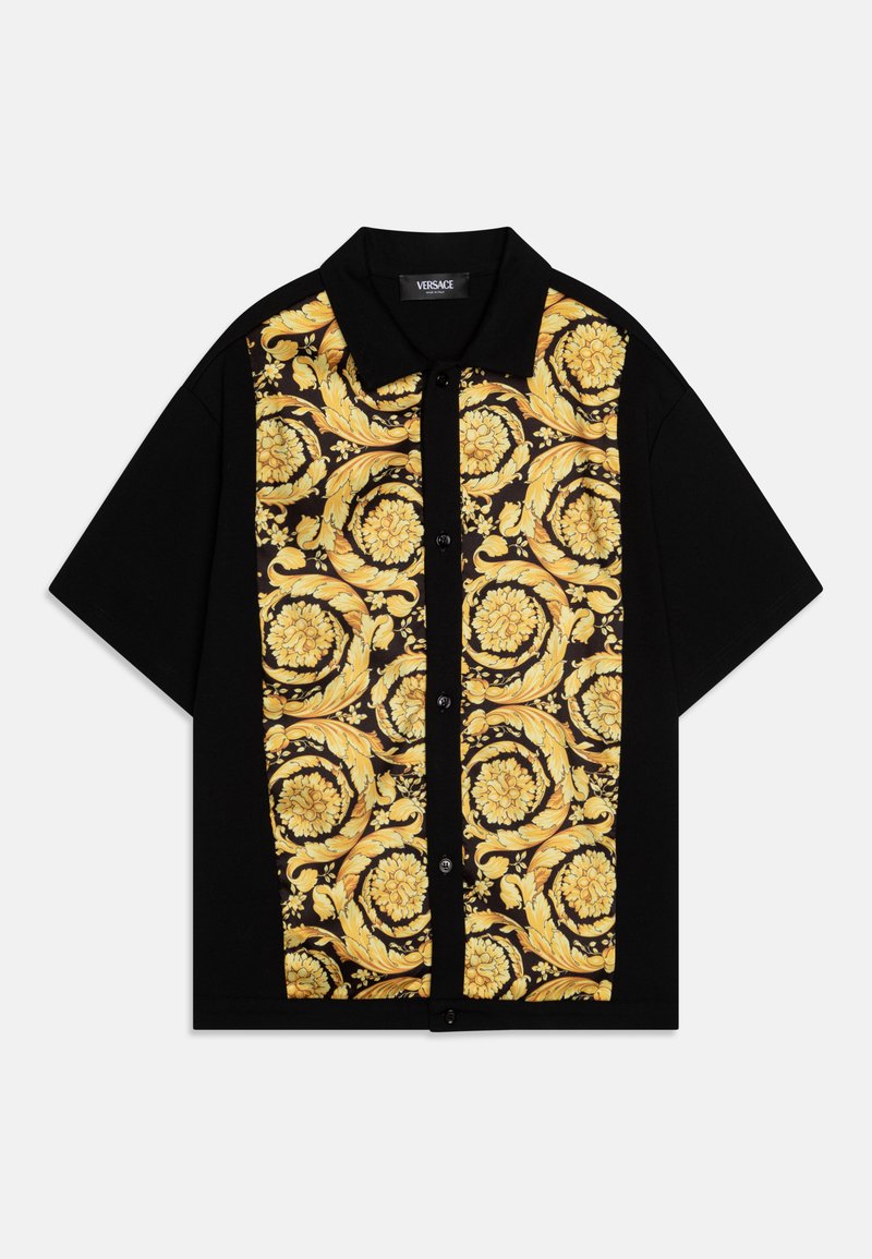 Chemise noire à manches courtes présentant un motif floral jaune vif à l'avant, avec un col et une fermeture à boutons. Texture de tissu douce.