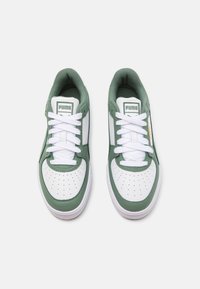 Zelené a bílé tenisky z perforované kůže, s plochými bílými tkaničkami, polstrovaným lemem a značkovou nášivkou na jazyku. Pryžová podrážka.