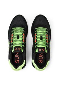 Zapatillas deportivas negras con cordones de un verde brillante, con un upper texturizado y detalles en naranja en la lengüeta. Diseño de ajuste seguro.