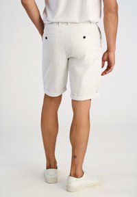 Herren Shorts aus weißem Baumwollstoff mit umgeschlagenen Säumen, zwei Gesäßtaschen mit schwarzen Knöpfen und einem versteckten Etikett auf der rechten Seite. Elegantes und minimalistisches Design.