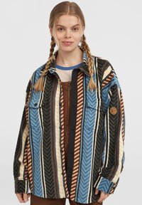 Multicolored flannel shirt featuring zigzag patterns in blue, brown, cream, and black. Includes two front pockets and a button closure.
