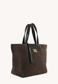 Sac fourre-tout en suède marron avec des poignées en cuir noir, un détail en pompon et une petite fermeture rectangulaire en or sur le rabat avant.